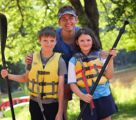 Counselor and campers holding kayak paddles