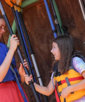 Counselor and camper holding kayak paddles