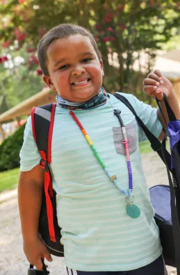 Boy with backpack and character bead necklace