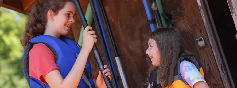 Counselor and camper holding kayak paddles