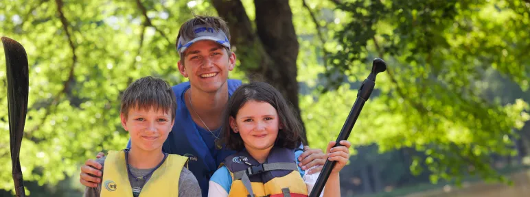 Counselor and campers holding kayak paddles