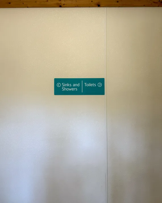 An image of the sign pointing to toilets and showers in the girls bathhouse.