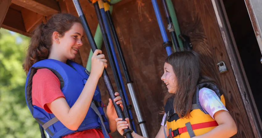 Counselor and camper holding kayak paddles